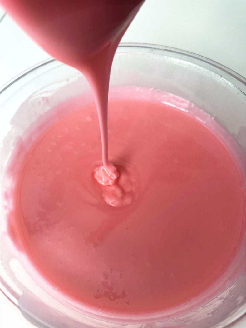 pink flood icing flowing into a bowl